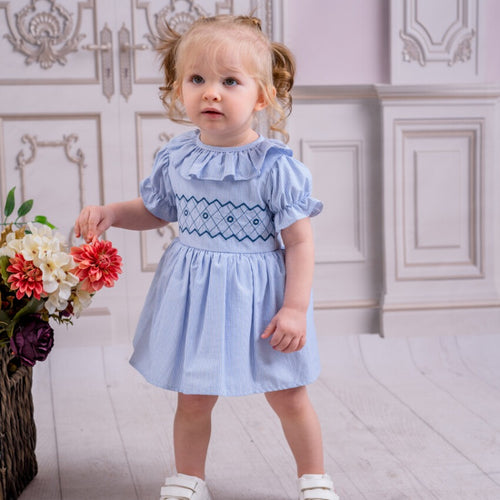 Spanish style smocked dress for little girls in a pale blue and white colourway with smocked detailing to the middle and frilly collar and gathered frill puff sleeves. A stunning piece for any special occasion
